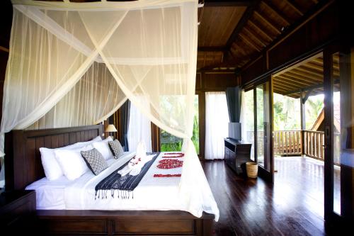 a bedroom with a bed with white sheets and curtains at Sebatu Tulen Villa in Tegalalang