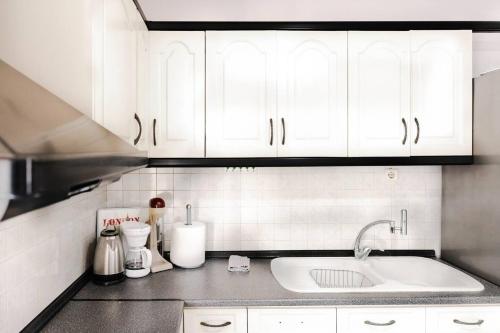 uma cozinha com armários brancos e um lavatório em Soleado, Nilie Hospitality MGMT em Tessalônica