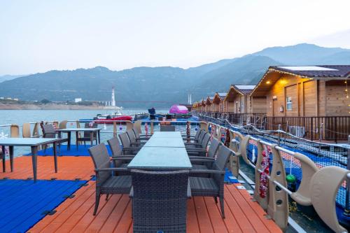 a deck with tables and chairs on the water at Le ROI Floating Huts & Eco Rooms Tehri in Tehri-Garhwāl