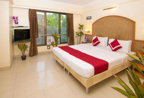Un dormitorio con una cama grande con almohadas rojas y blancas. en Octave Bund Garden, en Pune