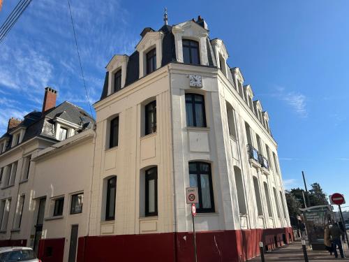 a white building with a clock tower on a street at Grand appartement, 3 chambres, centre de Dieppe in Dieppe