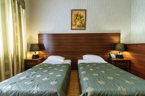 a hotel room with two beds and two lamps at Hotel Verhovina in Kyiv
