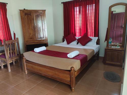 a bedroom with a large bed with red curtains at Jungle Villa Munnar in Pooppara