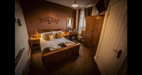 Ensuite Bed And Breakfast Rooms At The Ring Pub في Gwredog: غرفة نوم مع سرير ومكتب مع موقف ليلي
