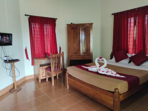 a bedroom with a bed with red curtains at Jungle Villa Munnar in Pooppara