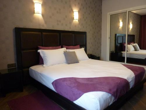 a hotel room with a large bed with white and purple sheets at Hotel Swani in Meknès