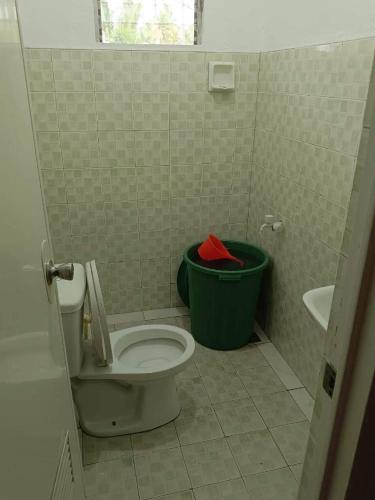 a bathroom with a toilet and a green trash can at Angel's Place - House For Rent in San Francisco