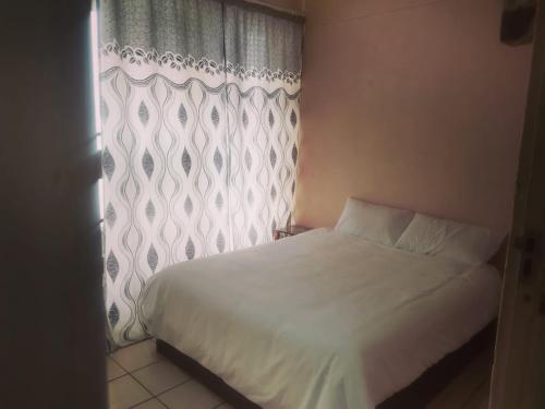 1 dormitorio con cama blanca y ventana en Stay Inn Krugersdorp en Krugersdorp