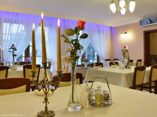 a table with candles and flowers in a room at Restauracja Ambrozja i Pokoje gościnne in Mława