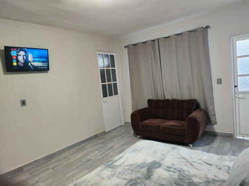 Suite privada في San Martín de las Pirámides: غرفة معيشة مع أريكة وتلفزيون على الحائط