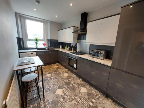 a kitchen with white cabinets and a table in it at Newly Renovated Oliver Apartment in Hawick
