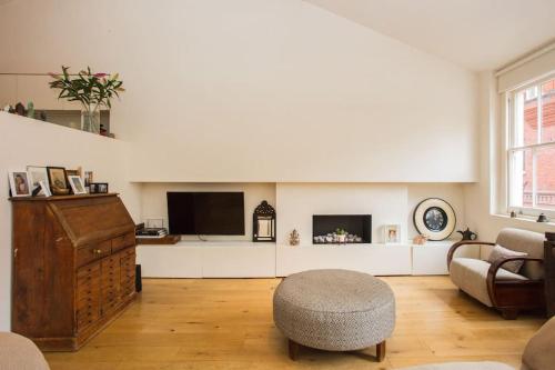 a living room with a tv and a chair at Beautiful Kensington flat in London