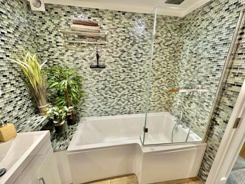 a white bath tub in a bathroom with tiles at Stunning Sea View Two Bed Apartment - With Balcony in Bournemouth