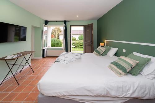 - une chambre avec un grand lit blanc aux murs verts dans l'établissement Le Gingko - Hotel du Golf Parc Robert Hersant, à La Chaussée-dʼIvry