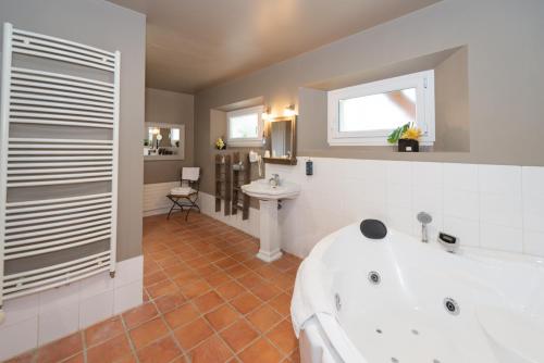 y baño con bañera blanca y lavamanos. en Le Gingko - Hotel du Golf Parc Robert Hersant, en La Chaussée-dʼIvry