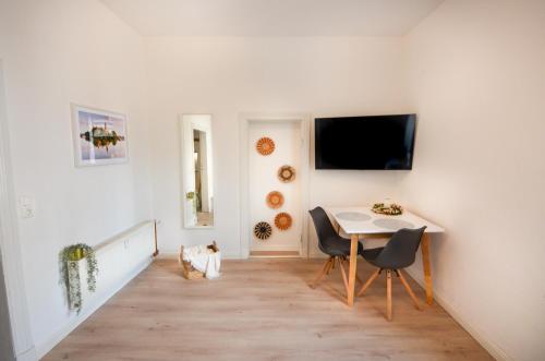 a dining room with a table and a tv on a wall at Apartmenthaus Fritz Reuter in Schwerin