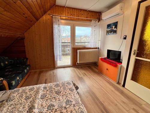 a room with a bed and a television and a window at A Festő Vendégháza / The Painter's Guest House in Zánka