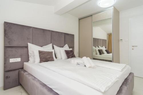 un grande letto bianco in una camera da letto con un grande specchio di Apartmani Šimi - The Sun a Crikvenica