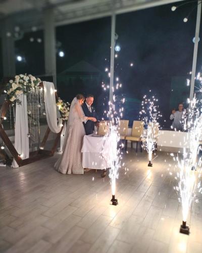 a bride and groom standing at a table with lights at Hotel Verhovina in Kyiv