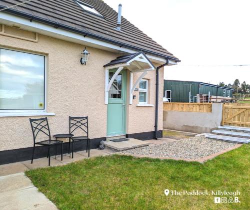 a house with a blue door and two chairs at The Paddock in Killyleagh