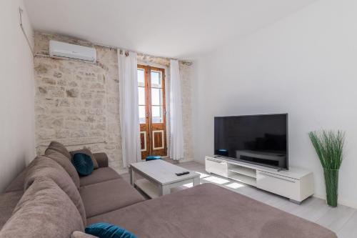 a living room with a couch and a flat screen tv at Seafront apartments Karlo in Kaštela