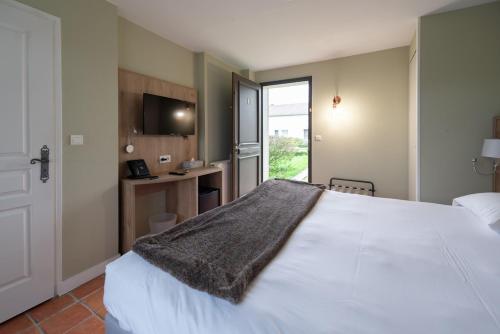 a bedroom with a white bed and a television at Le Gingko - Hotel du Golf Parc Robert Hersant in La Chaussée-dʼIvry