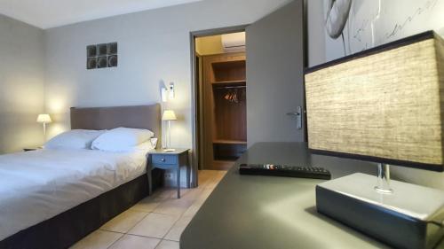 a bedroom with a bed and a desk with a computer monitor at Hôtel Les Magnanarelles in Maussane-les-Alpilles