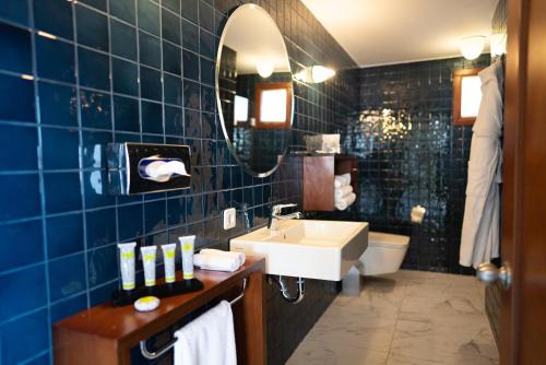 a blue tiled bathroom with a sink and a mirror at No81 Hotel in Golturkbuku