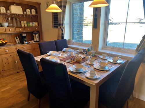 a dining room table with blue chairs and a table with dishes on it at Bracadale House in Port na Long