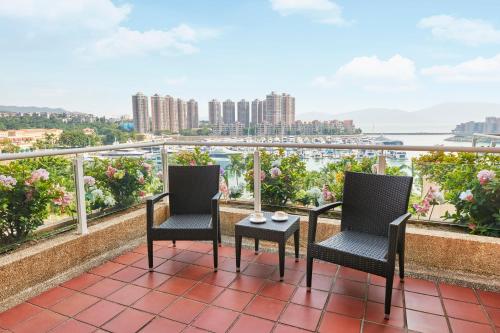 two chairs and a table on a balcony with a view at Hong Kong Gold Coast Hotel in Hong Kong