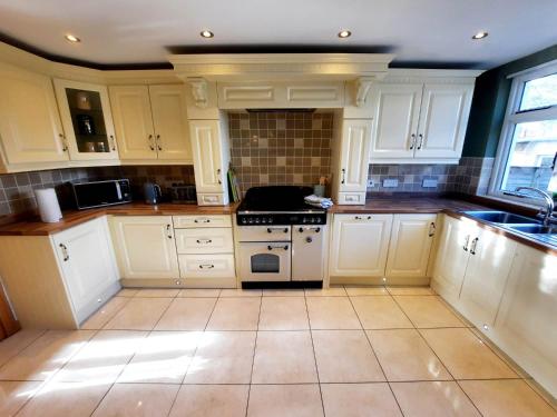 a kitchen with white cabinets and a stove top oven at - The Holly Tree House - in Bushmills