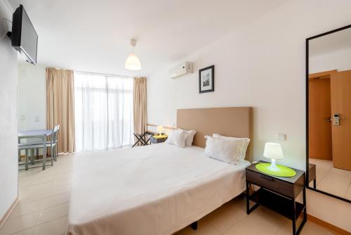 a bedroom with a large bed and a mirror at Apartamentos Mirante da Rocha in Portimão