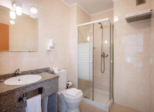 een badkamer met een douche, een toilet en een wastafel bij Apartamentos Mirante da Rocha in Portimão