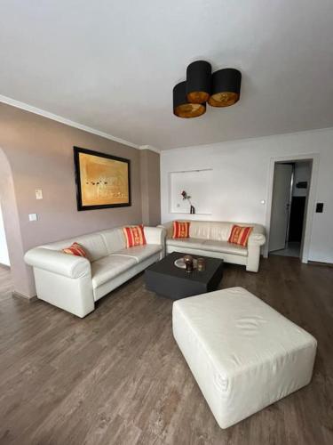 a living room with two white couches and a table at Ferienwohnung am Burgberg in Bad Harzburg in Bad Harzburg