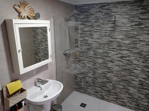 uma casa de banho com um lavatório e um chuveiro com um espelho. em Residencial Xeresa del Monte Solo Familias Serviplaya em Jeresa