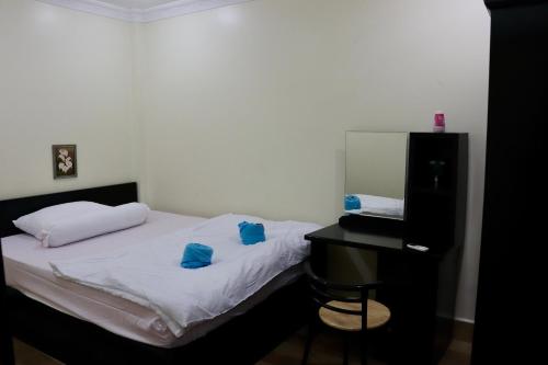 1 dormitorio con cama con almohadas azules y escritorio en Gvai Apartment en Phnom Penh