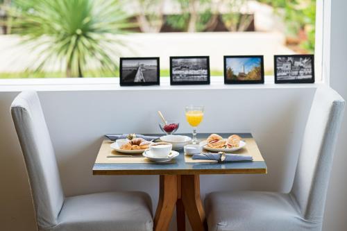 a table with two chairs with food and drinks on it at Unìco Boutique Hotel d'Arte in Mondello
