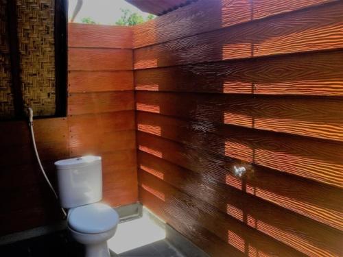 La salle de bains est pourvue de toilettes et d'un mur en bois. dans l'établissement Good Vibes Bungalows, à Gili Trawangan