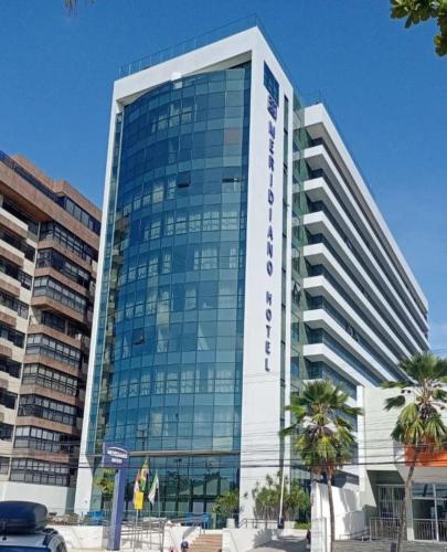 a large glass building with palm trees in front of it at PAJUCARA FRONT BEACH 2 in Maceió