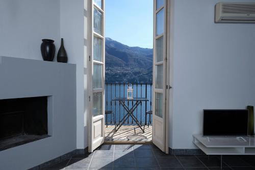 a room with a fireplace and a balcony with a view at Cozy Suites on the Lake - The House Of Travelers in Brienno