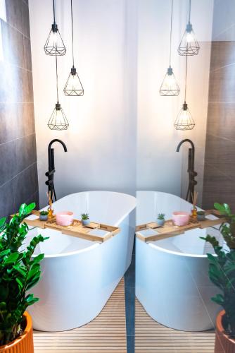 two white bath tubs in a bathroom with potted plants at Thome Ego Flat in Cluj-Napoca