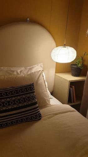 a bed with a pillow and a lamp and a plant at The Melo pomelo courtyard. ( Right in between Thamel and basantapur durbar square) in Kathmandu