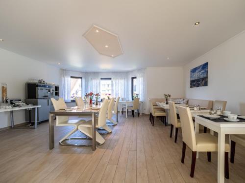 une salle à manger avec tables et chaises et une cuisine dans l'établissement Tom's Hus Heiligenhafen, à Heiligenhafen
