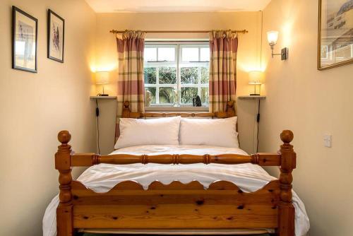 a bedroom with a wooden bed with a window at Tyddyn Crythor in Llangadwaladr