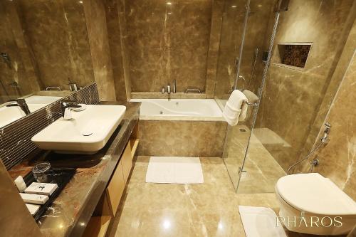 a bathroom with a sink and a tub and a toilet at Pharos Hotels in Chennai