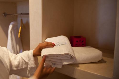 a woman holding a stack of towels in a bathroom at Dakhla Camp in Dakhla