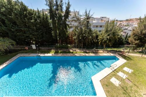 een groot zwembad in een tuin met bomen bij CT 232 - Eden Golf Sur - Southfacing Apartment in Mijas