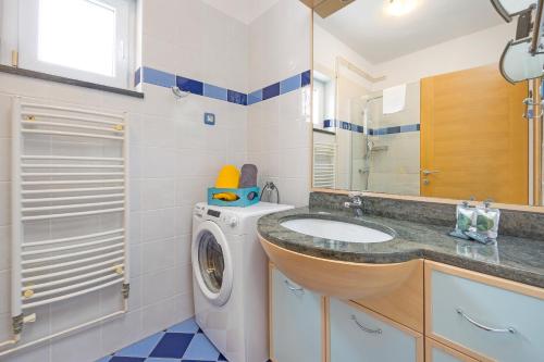 uma casa de banho com uma máquina de lavar roupa e um lavatório em Apartmani Paliska em Pula