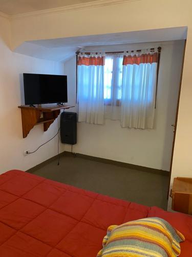 a bedroom with a bed and a television and curtains at Hotel Samay Huasi in Villa General Belgrano