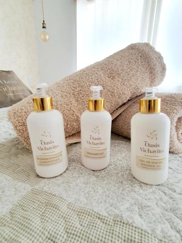 a trio of three shampoo bottles sitting on a bed at Oasis de Vichayito in Vichayito
